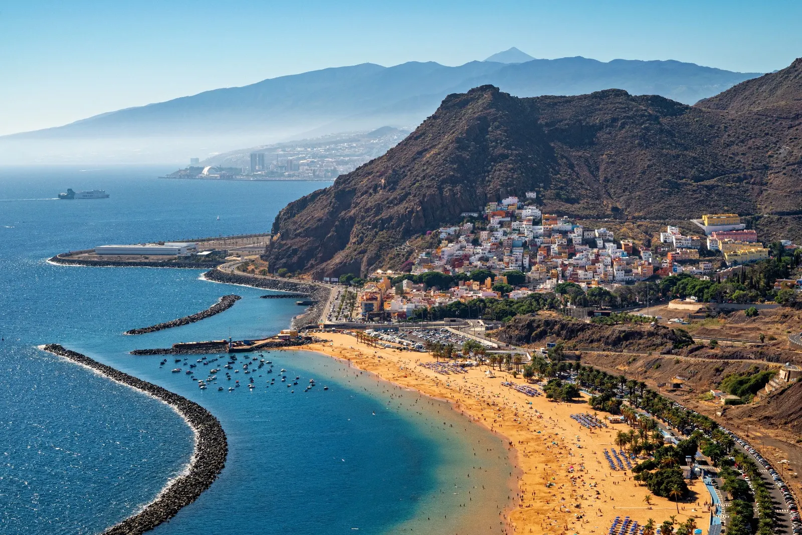 Sweeping golden beach beneath mountains and a colourful town